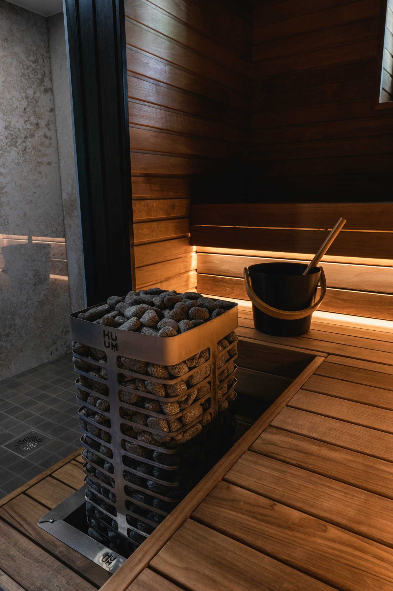 Interior view of a sauna showing the heated rocks used for pouring water. The image highlights the serene and relaxing environment, with focus on the sauna’s design and wellness features