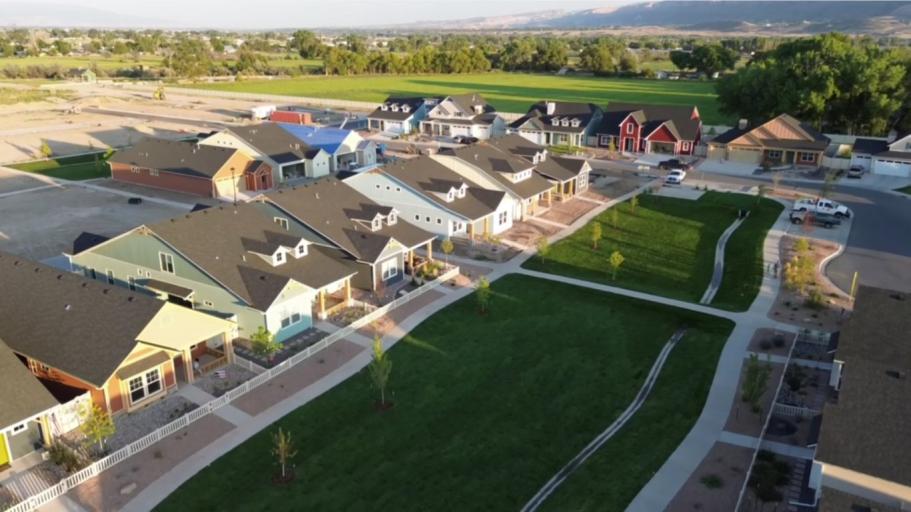 Aerial drone view of the Copper Creek neighborhood showing colorful houses, lush green parks, and sidewalks for daily walks, highlighting community lifestyle and outdoor living